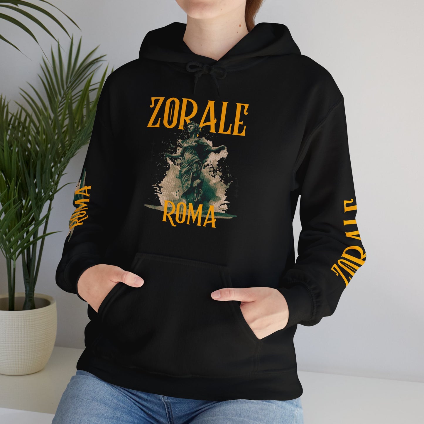 Person wearing a black hoodie with 'Zorale Roma' design, standing indoors with a plant in the background.