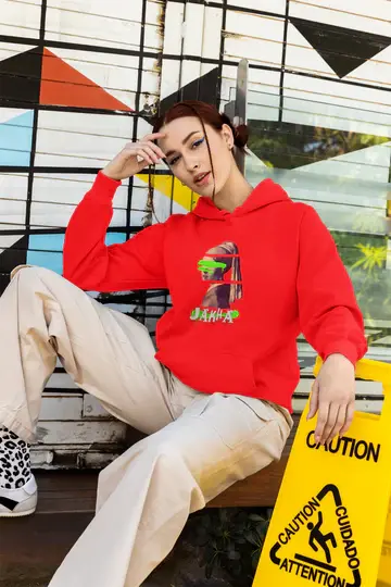 Person wearing a red hoodie with a graphic design, sitting on a bench with a colorful geometric-patterned wall in the background.